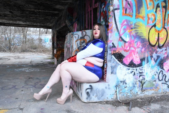 Plus size woman wearing plus size sexy costumes sitting outdoors near colorful graffiti wall