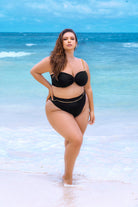 Plus size model wearing CT Lingerie lyra sexy black bikini standing on the beach with ocean background