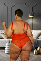 Plus size red lace bodysuit worn by a confident model in a stylish modern living room